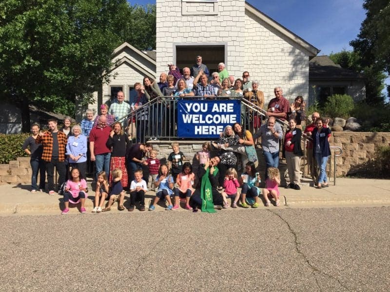 Congregation outside church with welcoming banner